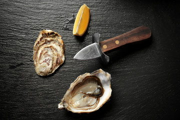 Delicious oyster with lemon and knife on dark table