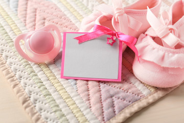 Greeting card with booties and pacifier on table