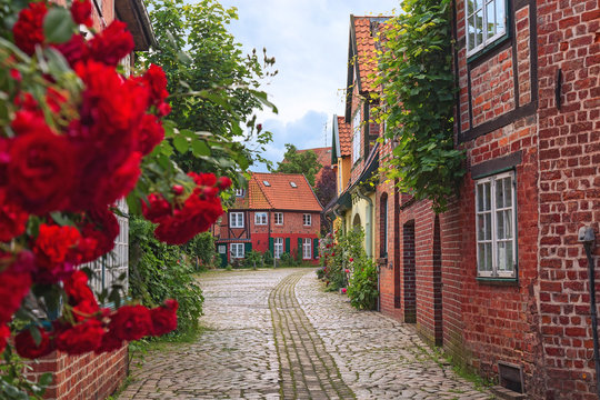 Beautiful cozy street of the old town of Luneburg in Germany. A street in a small German city, cozy apartment houses, lots of greenery, flowers, cobblestone pavement. Quiet and calm town.