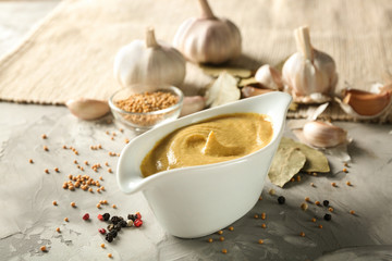 Composition with gravy boat of delicious mustard sauce on table