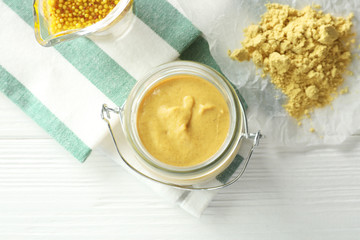 Glass jar with delicious mustard sauce on table