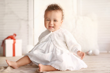 Fototapeta premium Cute little baby sitting on floor against blurred background