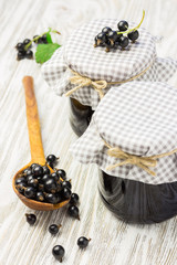 Delicious black currant jelly in jars on wooden shabby background. Selective focus, space for text.  