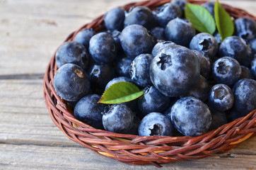 Freshly picked blueberries in a basket on old wooden background.Fresh blueberries with green leaves on rustic table.Blueberry. Bilberry.Healthy eating,diet and nutrition concept.