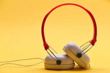 Modern and stylish earphones on warm yellow background