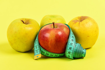 Apples of red and yellow colour with cyan measuring tape