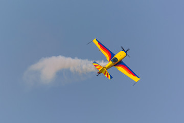 Naklejka na ściany i meble A Colorful Airplane Turning Left and Leaving a Trail of Smoke at the Airshow