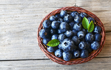 Freshly picked blueberries in a basket on old wooden background.Fresh blueberries with green leaves on rustic table.Blueberry. Bilberries.Healthy eating,diet and nutrition concept.