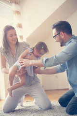 Happy family sitting  on floor with their little baby. Family spending time at home with their daughter.