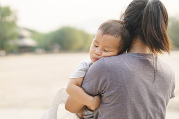 Sleeping Asian baby being held by his mother