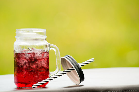 catering bar service. selective focus on a red cold lemonade in a mason jar with straw and ice cubes with copyspace. Concept of summer, vacation, beverage relax, friends and fun