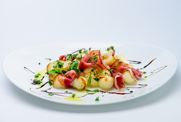 classic Italian summer delicious fresh salad with cheese, parma ham and soy sauce on white plate,...