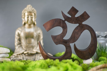 Wooden om symbol with golden buddha and moss