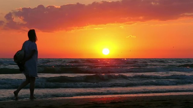 Girl Is Walking Along The Beach At Sunset