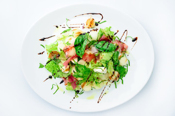 classic Italian summer delicious fresh salad with cheese, parma ham and soy sauce on white plate, on light background, top view