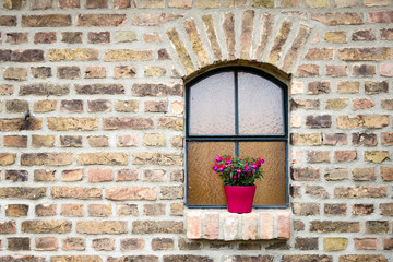 Mauer aus Ziegelsteinen mit Fenster und Blumentopf