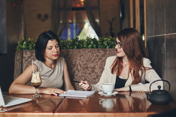 Two young caucasian businesswomen with laptop. Women in cafe