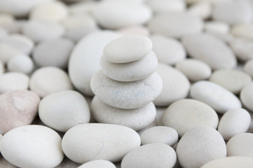 Fototapeta na wymiar Harmony and balance, cairn, poise stones on pebbles background, rock zen sculpture, white and light gray pebbles