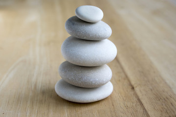 Fototapeta na wymiar White pebbles tower, stone cairn on wooden background