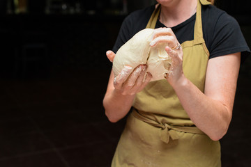 female chef kneading dough for pizza, process of preparing pizza. Cooking time, cooking concept, selective focus