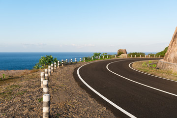 Asphalt coastal road going round cliff edge bend.