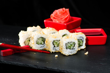 Traditional Japanese cuisine.  Appetizing sushi rolls with cucumber, cream cheese, rice, sesame seeds on dark background