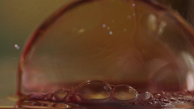 Macro close up, red bubble pops in slow motion