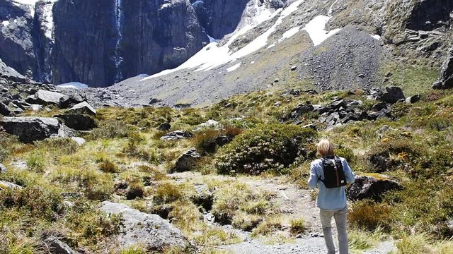 Slow motion, blonde man backpacking in scenic valley landscape