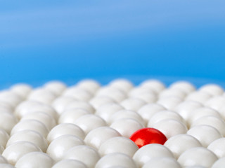 stand out red ball surrounded by white balls on blue background