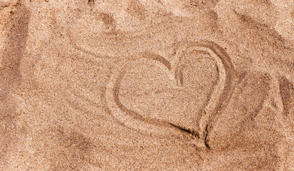 Fototapeta na wymiar Drawing of a heart on the sand on beach with space for the text. Sea travel and holiday. Selective focus