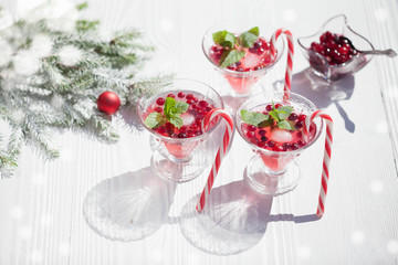 Cranberry drinks with lollipop candy cane on white rustic wooden table, Christmas background