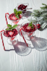 Cranberry drinks with lollipop candy cane on white rustic wooden table, Christmas background