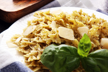 Farfalle pasta bows with pesto on a plate on a rustic background