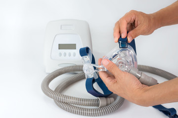 Hands removing clip from headgear,full components of Cpap system ,isolated white background..Cpap Continuous positive airway pressure system includes of main unit,mask,tube and headgear.
