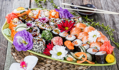 Sushi Set nigiri and sushi rolls decorated with flowers on bamboo background. Japanese cuisine. Selective focus