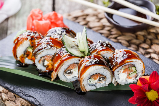 Sushi rolls set with salmon, cream cheese, cucumber, sesame and wasabi on black stone on bamboo mat, selective focus. Japanese cuisine