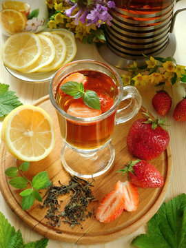 Spicy tea with strawberries illuminated by the sun rays on a wooden background