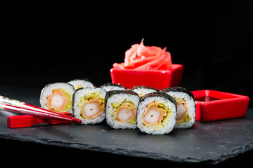 Traditional Japanese cuisine. Selective focus on set of sushi rolls with nori, shrimp, rice and other ingredients on dark background, near ginger