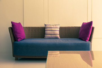 empty modern design wicker sofa with 3 pillows and empty wall, room for text or copyspace