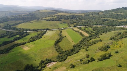 Fototapeta na wymiar a beautiful summer landscape shot from a bird's eye view. mountains, river, green fields and villages.