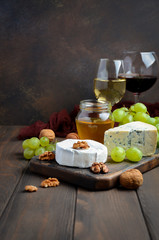 Variety of cheese with grapes, walnuts and wine, selective focus, copy space, vertical