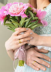 Hands of the newlyweds with flowers with wedding rings. Young family.
