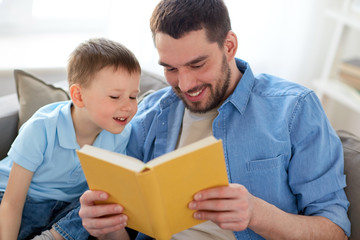 happy father and son reading book sofa at home