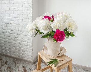 Bouquet of peonies on white wall background.