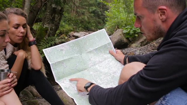 Tourists study the map of the area in a camping near the creek