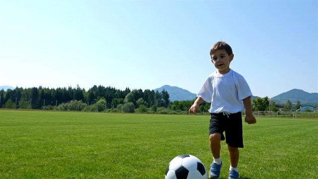 Tracking camera of a little 3 years old boy scoring a goal in a football field