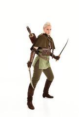 full length portrait of a blonde girl wearing green and brown medieval costume, holding a bow and arrow. isolated on white background.