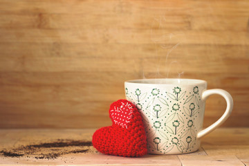 Coffee in a cup, with small red heart, on wooden background