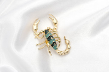 Brooch gold scorpion on white silk