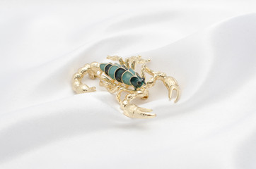 Brooch gold scorpion on white silk